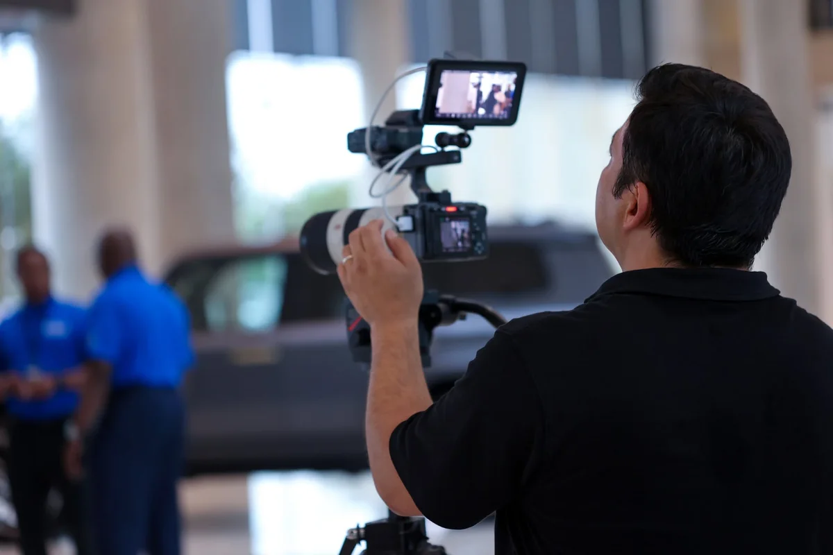A camera operator films two people speaking during the Lexus career exploration visit.